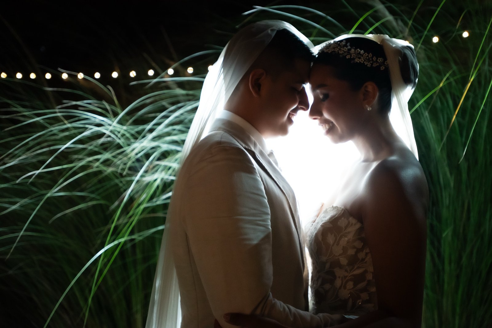Bride and groom embracing at night, backlit in golden light